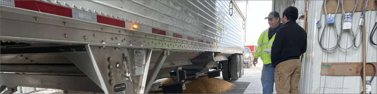 Two people talking beside semi-truck.